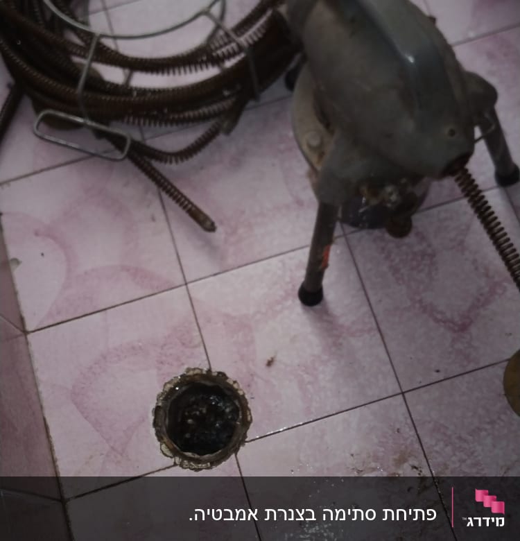 מכונת ניקוי צינורות ליד פתח ניקוז על רצפה